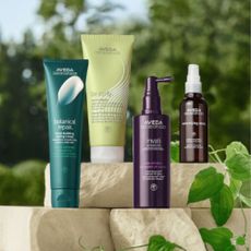 Bottles of Aveda products with trees and blue sky in background