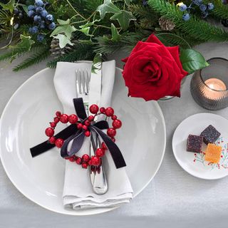 Place setting with red berry heart and red rose