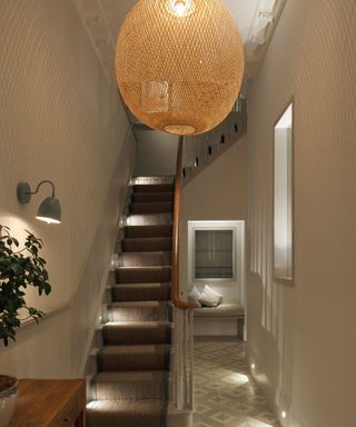 narrow hallway with large wicker pendant lighting and stairlights