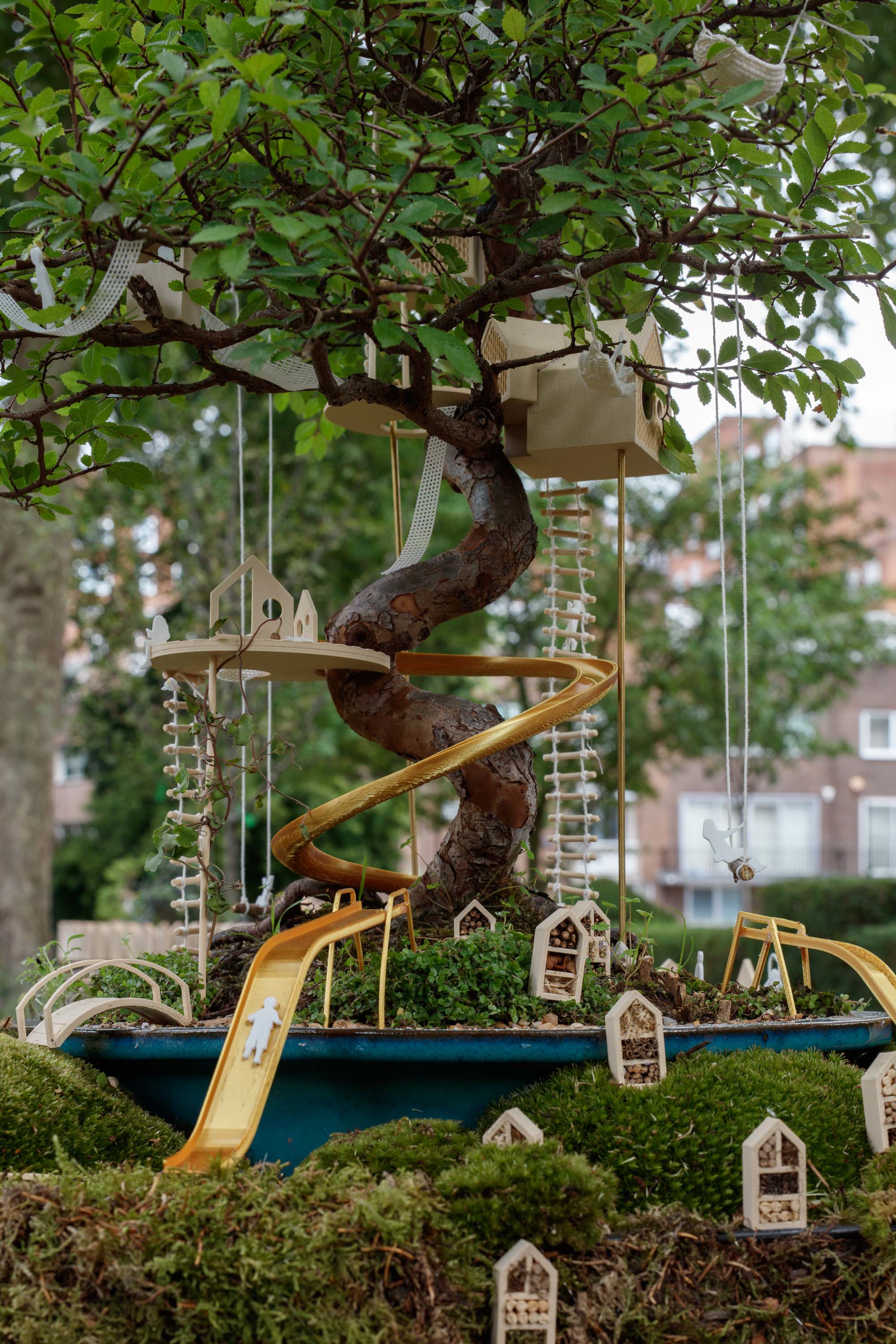 view of miniature houses in a park as part of an open air Bonsai treehouse exhibition in London