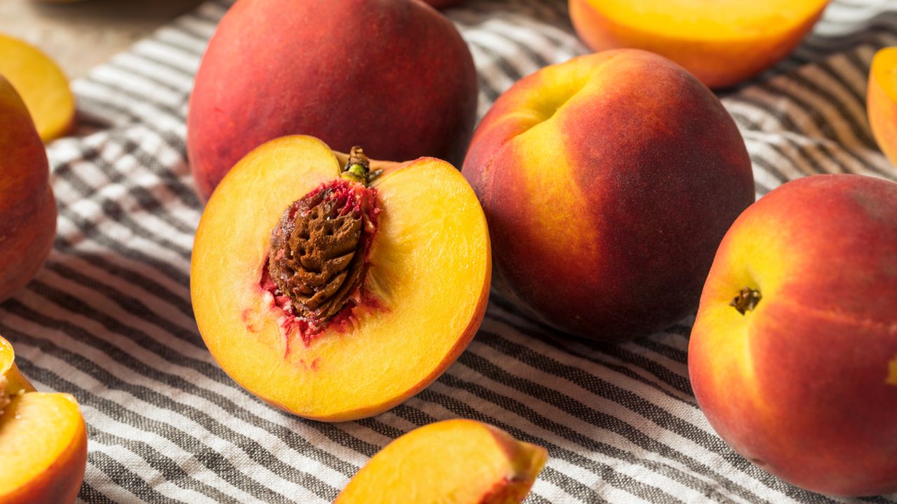 Cut peach with exposed pit on a striped towel