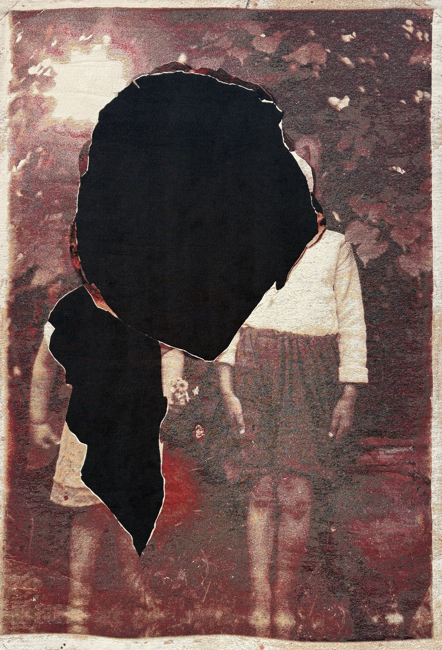 A close-up of a textile artwork obtained from a reworked, painted-red photograph that's been cut-out to remove the face of the two protagonists in it.