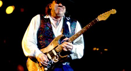 Stevie Ray Vaughan takes a ripping solo on his number one Strat, live at at the Alpine Valley Music Theater, Wisconsin. He wears a white shirt and a patterned waistcoat.