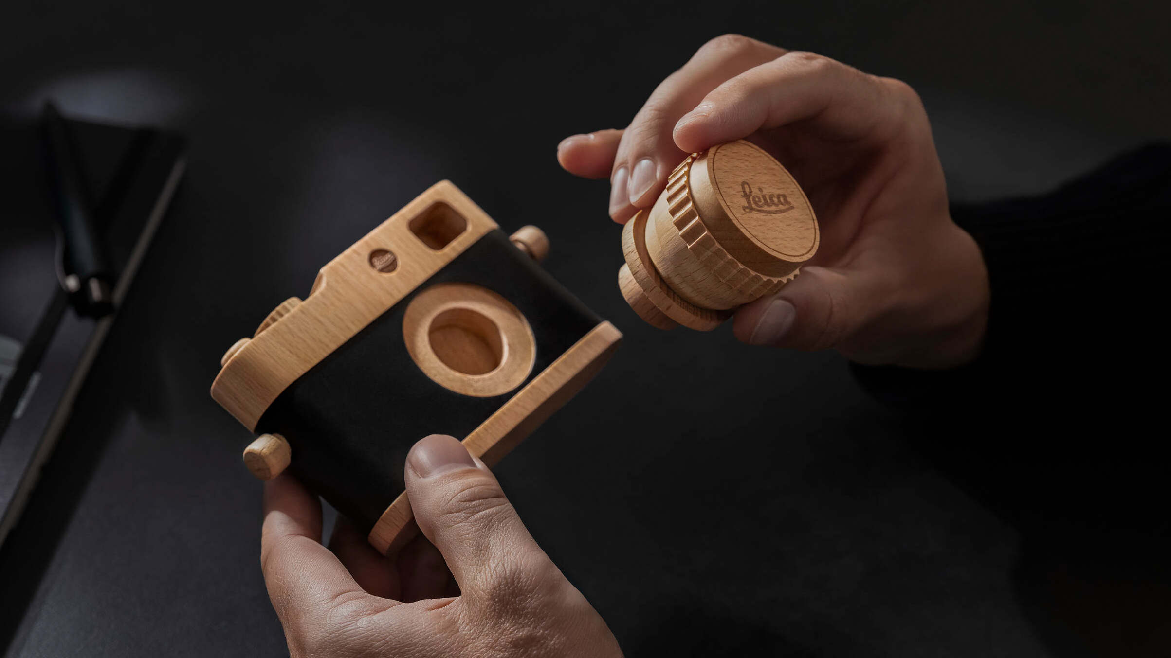 Wooden Leica camera with removable lens being held in person't hands indoors