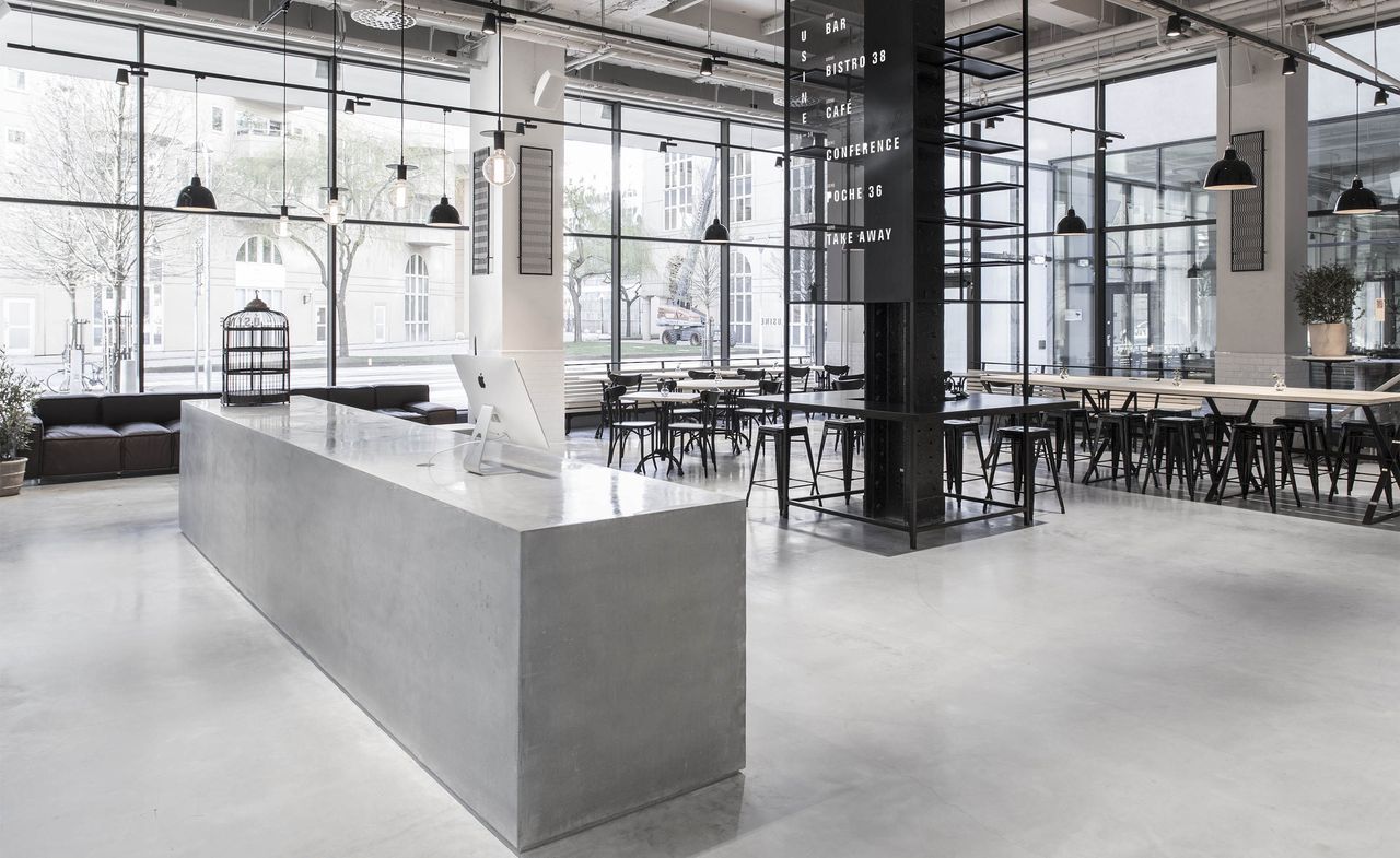 Dining area with concrete and exposed pipework, with simple black seating