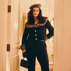 model wears black leopard print trimmed capri set with leopard print beret and a small black top handle bag while posing