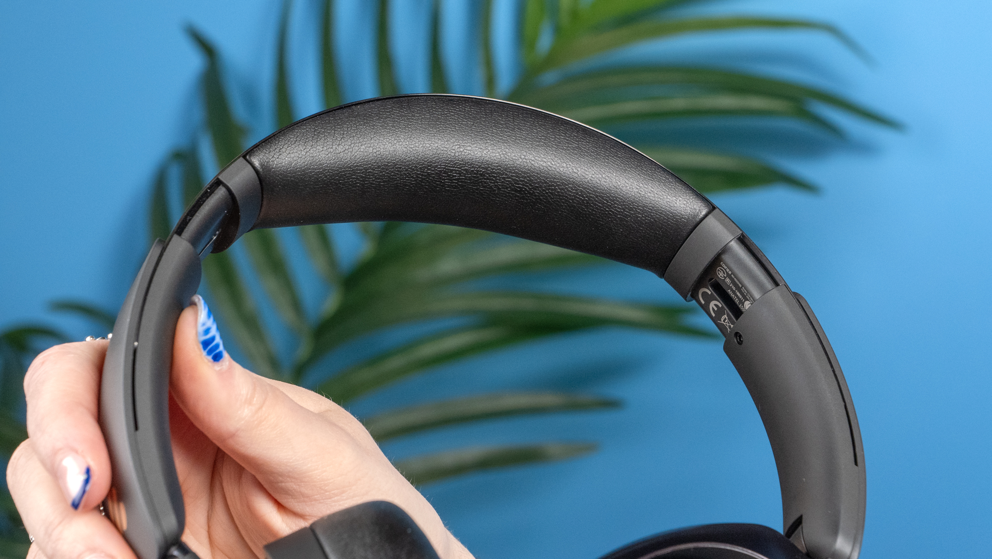 A pair of black Edifier WH950NB over-ear headphones photographed against a blue background