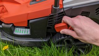 Adjusting the cutting height on Black + Decker's lawn mower.