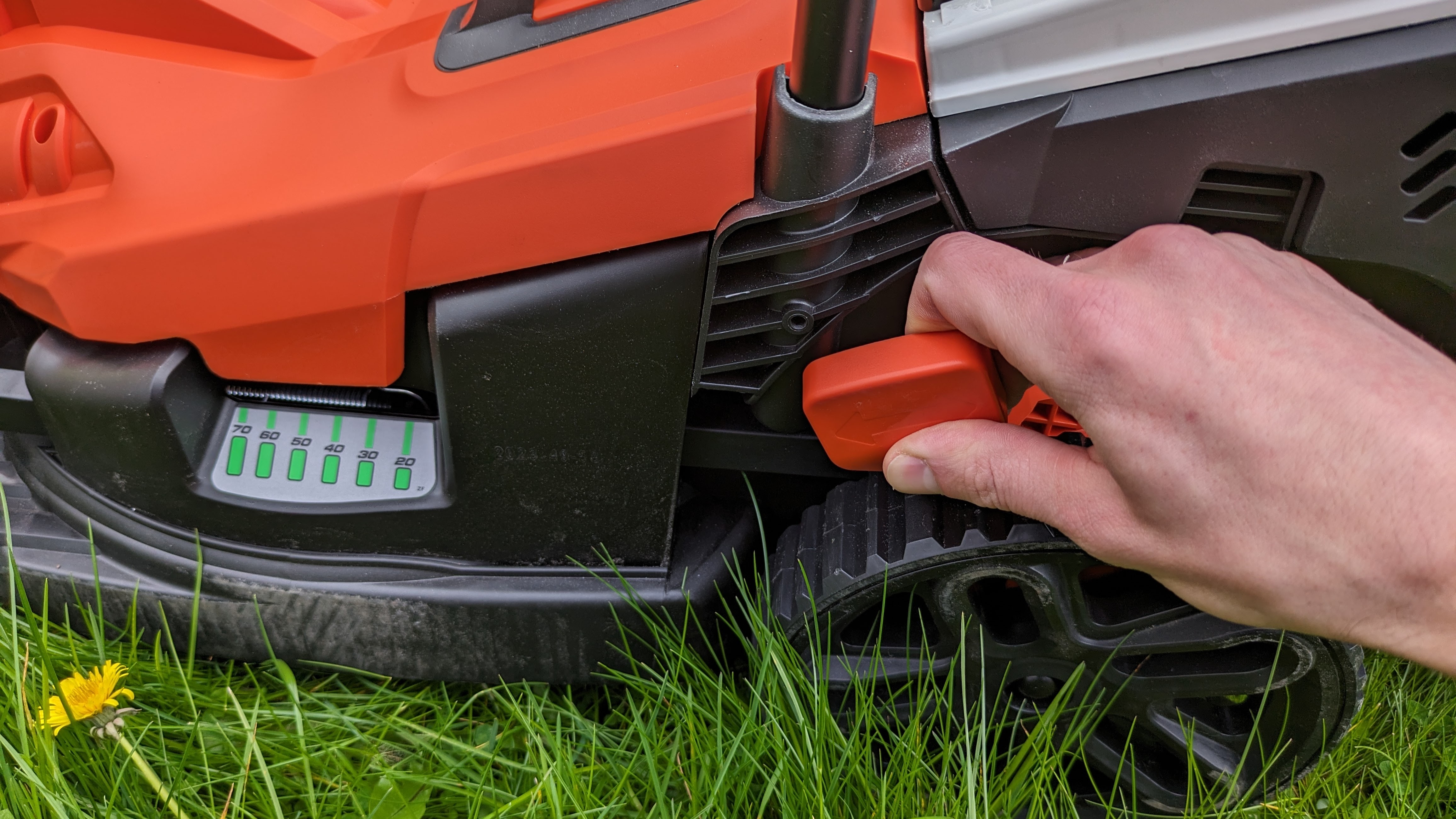 Adjusting the cutting height on Black + Decker's lawn mower.