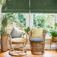 Green blinds in conservatory with wicker chairs