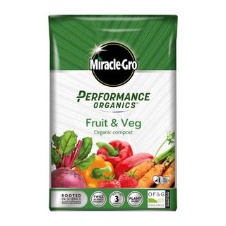 Green and silver bag of Miracle-Gro compost with vegetables and fruit such as peppers and strawberries along the bottom