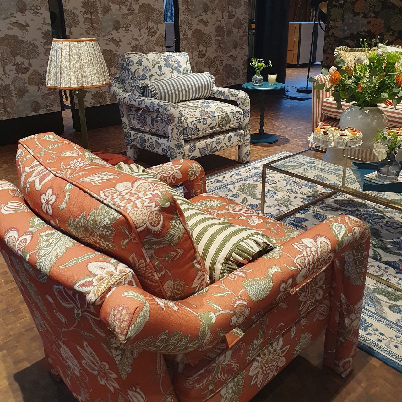 A living room setting with two floral accent chairs and a matching rug