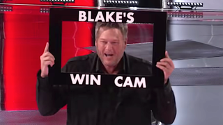 Blake Shelton poses with his Win Came frame on The Voice.