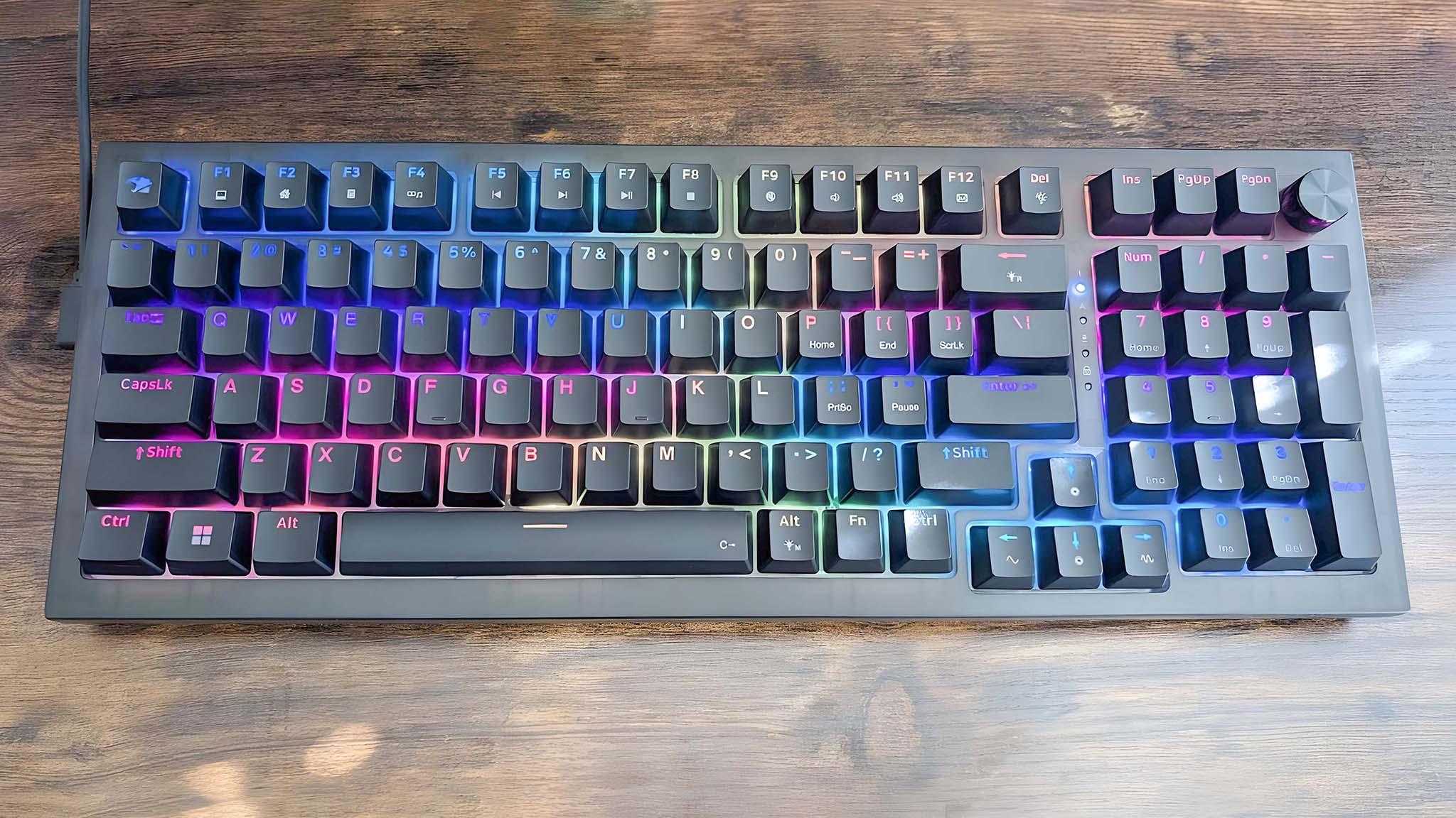 A top-down view of the iBuyPower MK9 Pro RGB Mechanical Keyboard with rainbow RGB turned on at a lower brightness.