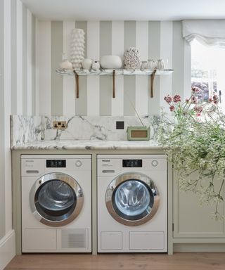 Miele washing machine in a chic farmhouse style laundry room with striped wallpaper and flowers in the sink