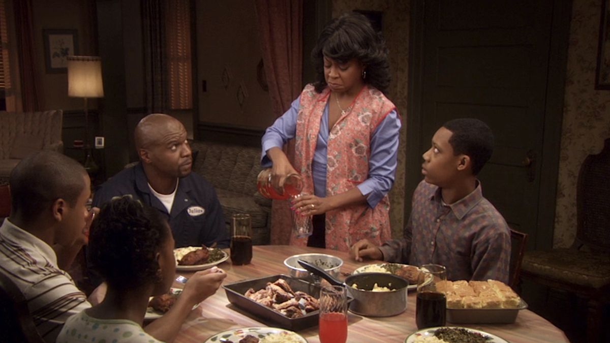 The Rock family sitting around the dinner table, with Julius and Chris warily eyeing Rochelle as she pours herself a drink in Everybody Hates Chris.