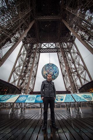 The artist pictured in front of 'Earth Crisis' at the Eiffel Tower.