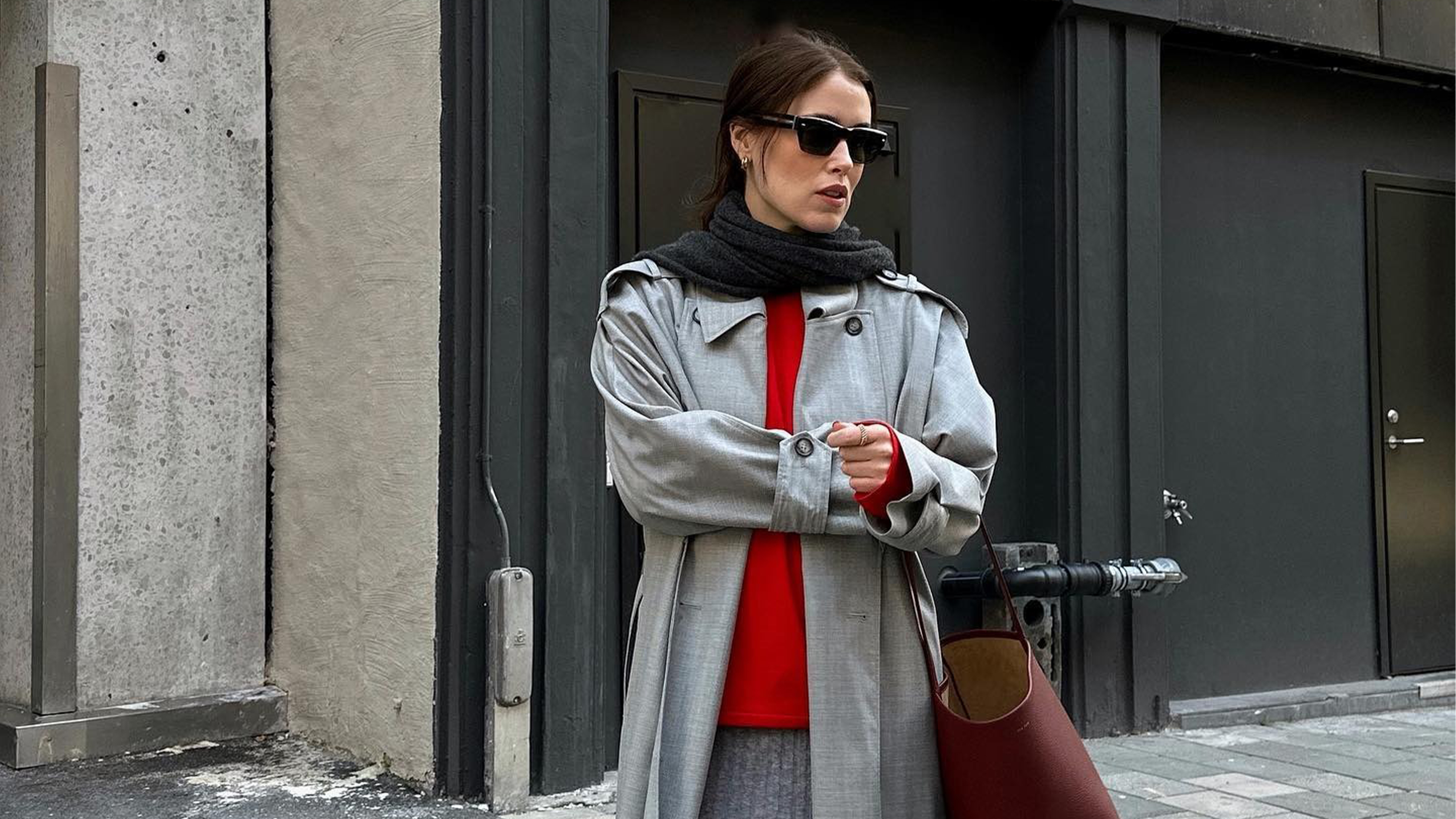 Influencer Anna Belrosendahl wears a red sweater, grey trench coat, and scarf.