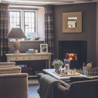 snug with dark walls wood-burner and plush chairs sims hilditch