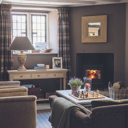 Snug room ideas with dark walls wood-burner and plush chairs sims hilditch