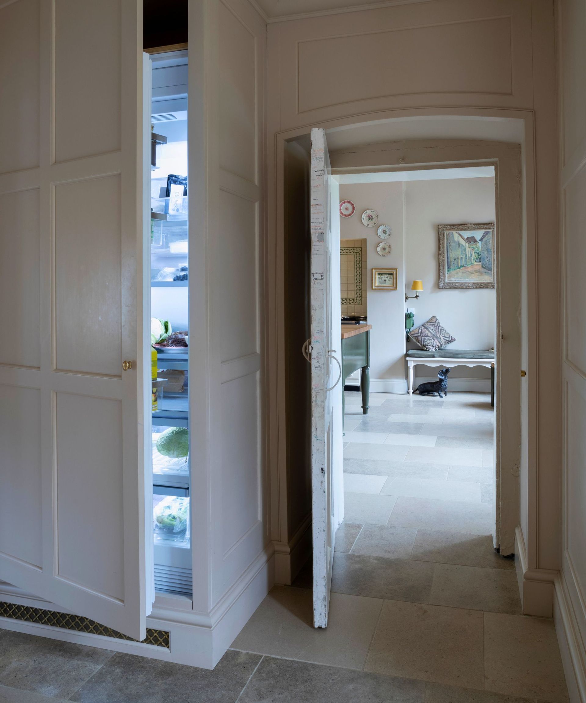 Behind a beautiful cream pantry, a hidden fridge is revealed