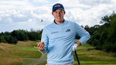 Matt Fitzpatrick looking down the camera while tossing a ball in the air