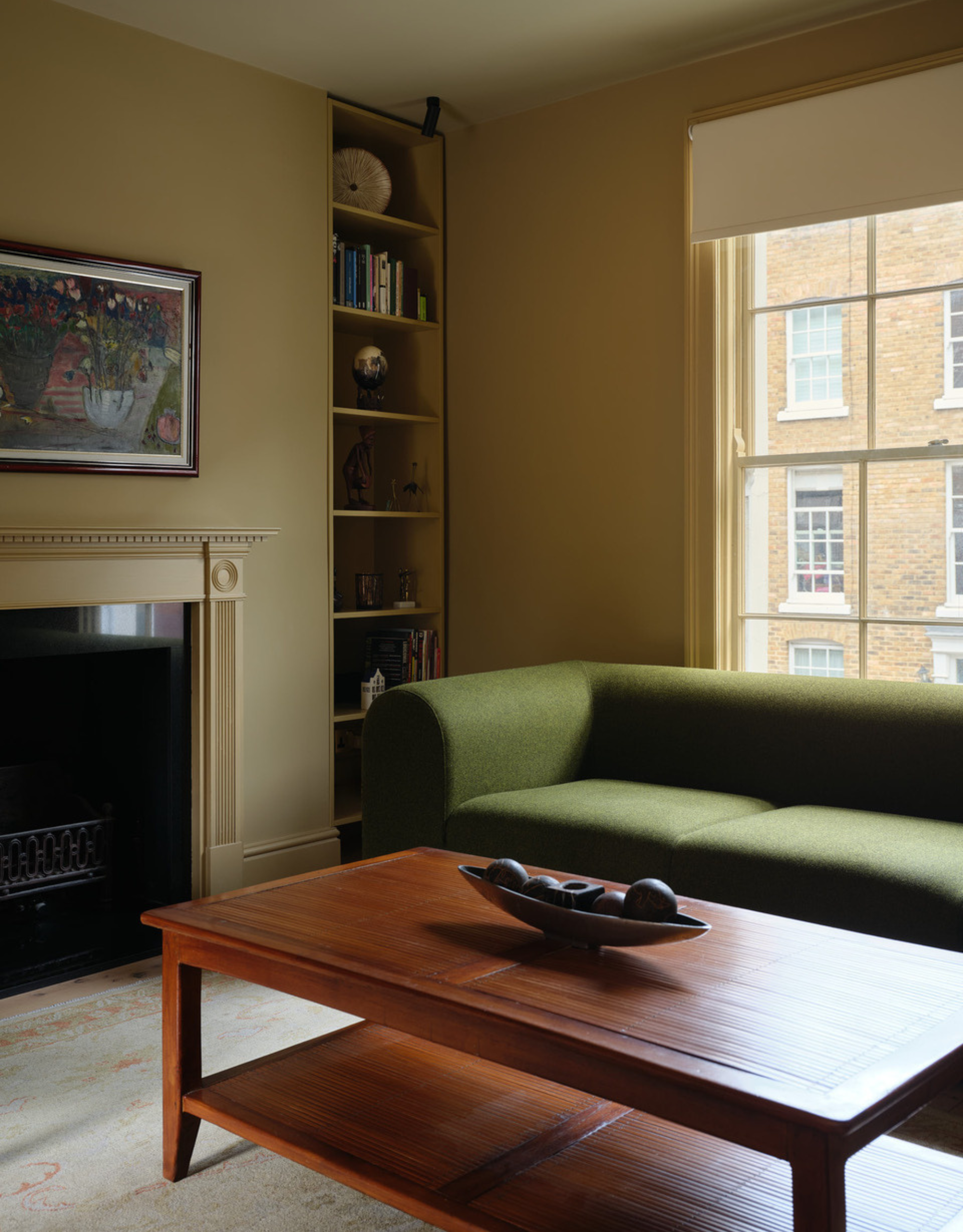 A yellow living room with a green couch, a wood coffee table, and a corner of shelves