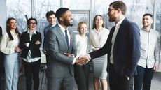 CEO shaking hands with new employee in front of other employees