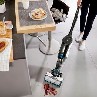 room with white tiled flooring and vacuum cleaner