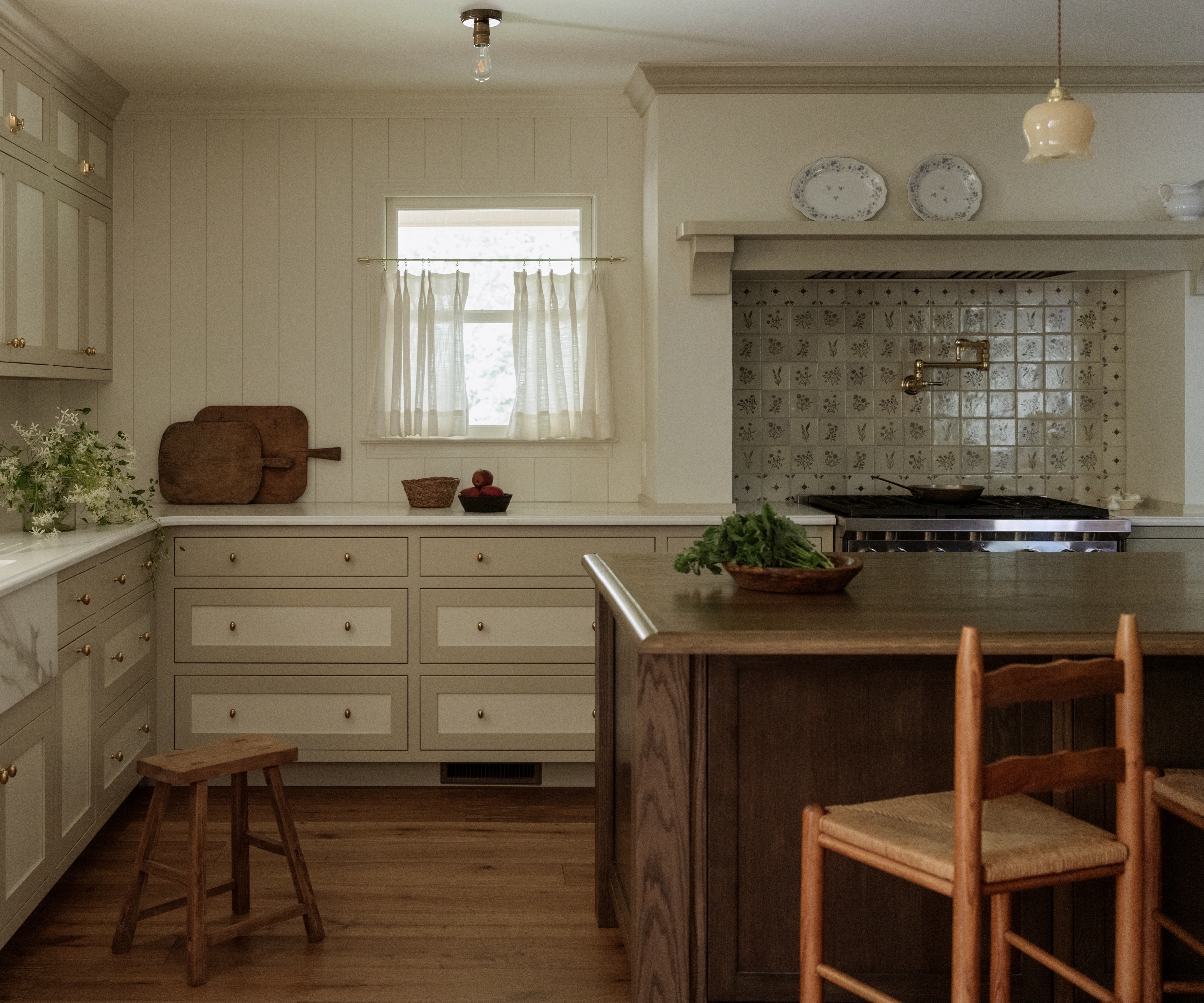 A warm cottage kitchen with a vintage tile backsplash and cabinets with colorful borders