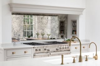 A small kitchen with luxe gold accents, an island with sink and large cooker