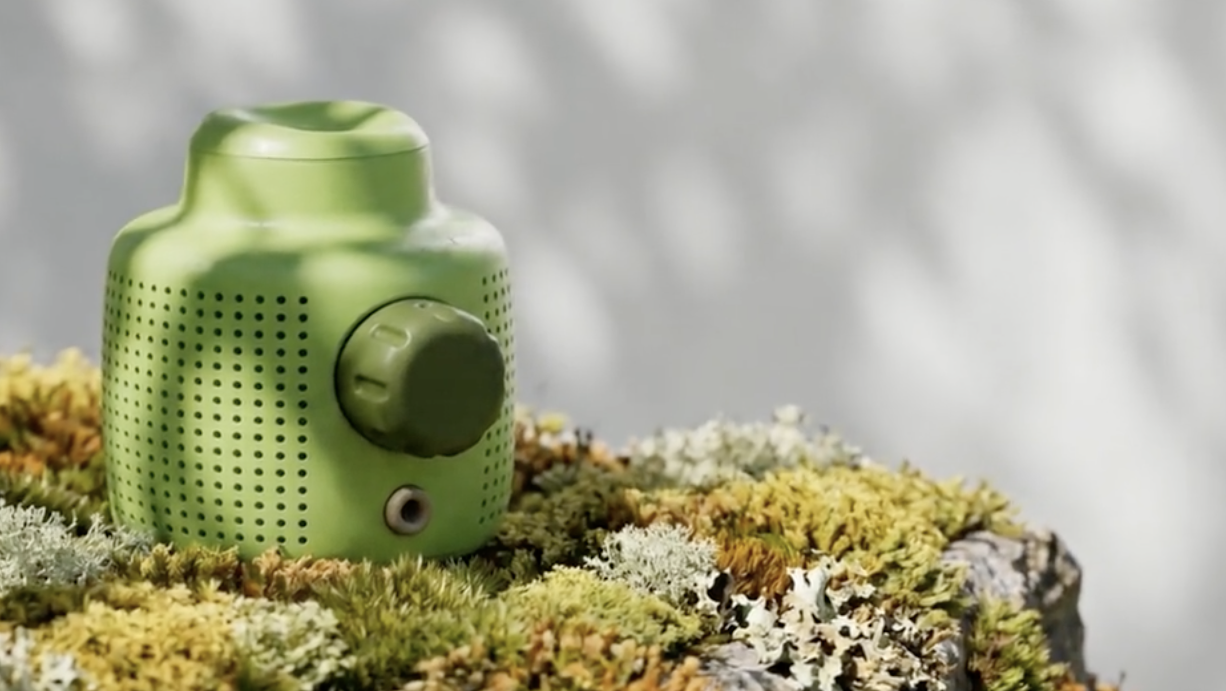 Mur Mur speaker and AI ecosystem in green, with moss in the background, showing the eyepiece in the top