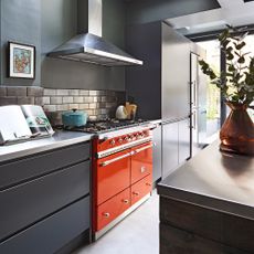 Orange range cooker in a kitchen with black cabinets and grey walls