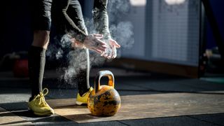 Man with chalky hands about to pick up kettlebell in gym