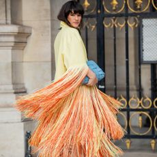 Gili Biegun seen wearing blue bag, yellow orange coat with fringes, orange platform heels outside Nanushka during Paris Fashion Week - Womenswear F/W 2022-2023 on March 01, 2022 in Paris, France