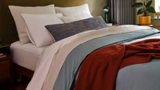 Bed sheets with blue comforter, white pillows and taupe sheet