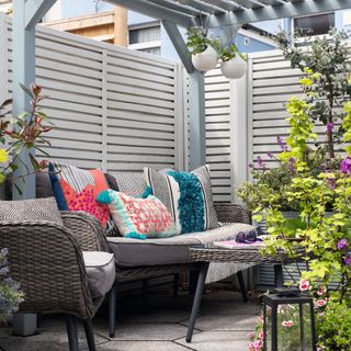 Grey rattan garden furniture seating area with outdoor colourful, patterned cushions