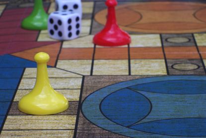 yellow, red and green plastic game movers on a Parcheesi-style game board with dice