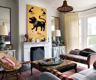 A white sitting room with patterned Wave Lounge in the bay window and stand out abstract black and yellow tiger artwork over the fireplace