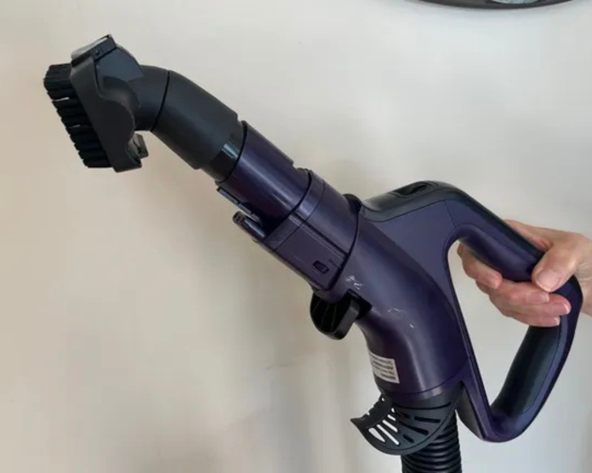 Holding the Shark POWERDETECT Upright Vacuum multipet tool against a white wall