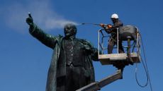 A municipal worker cleans the statue of Soviet state founder Vladimir Lenin during preparations for the 156th anniversary of Lenin's birthday in St. Petersburg, Russia