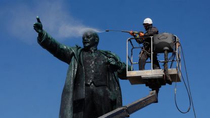 A municipal worker cleans the statue of Soviet state founder Vladimir Lenin during preparations for the 156th anniversary of Lenin's birthday in St. Petersburg, Russia