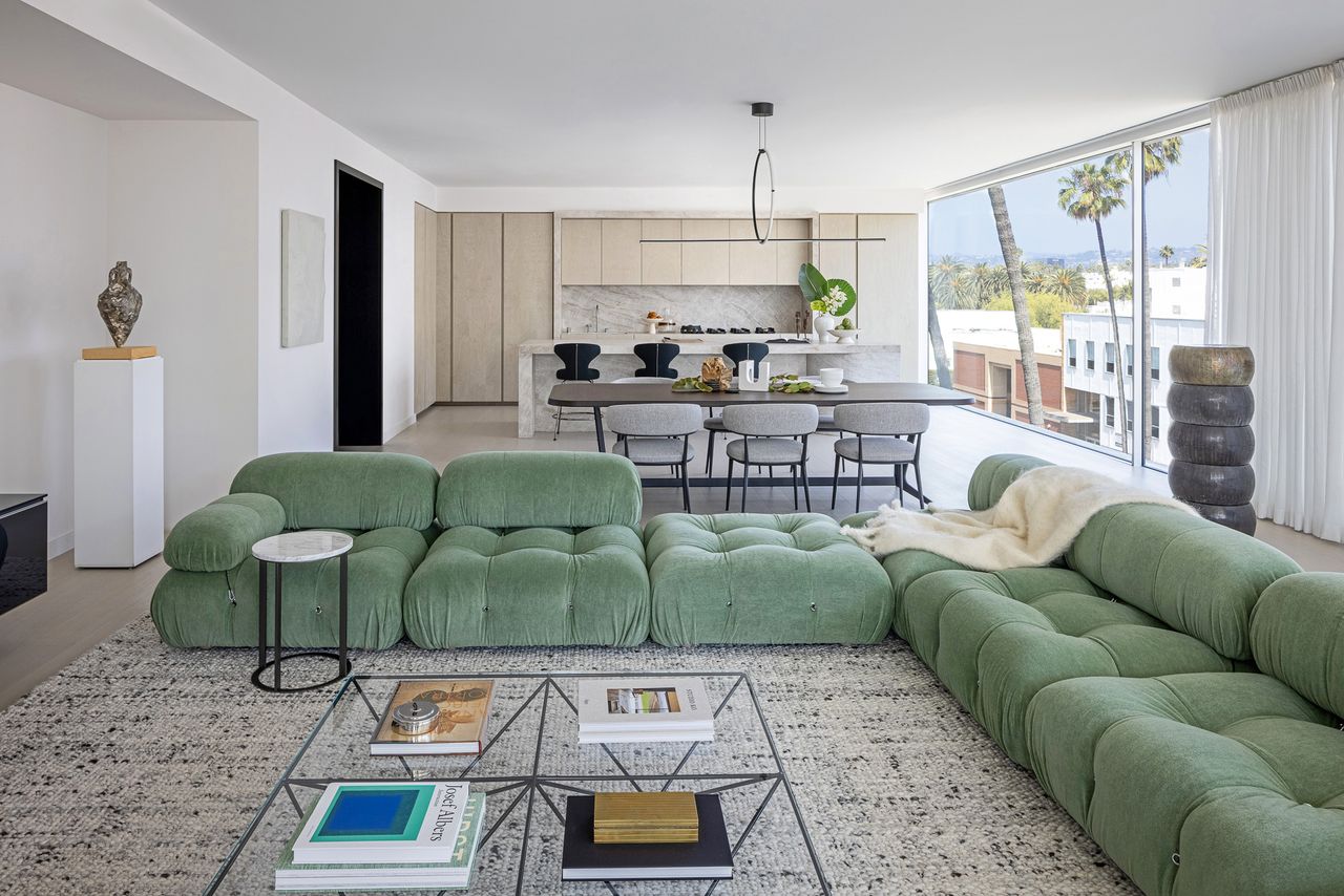 A living room with netural decor and a sage green sofa