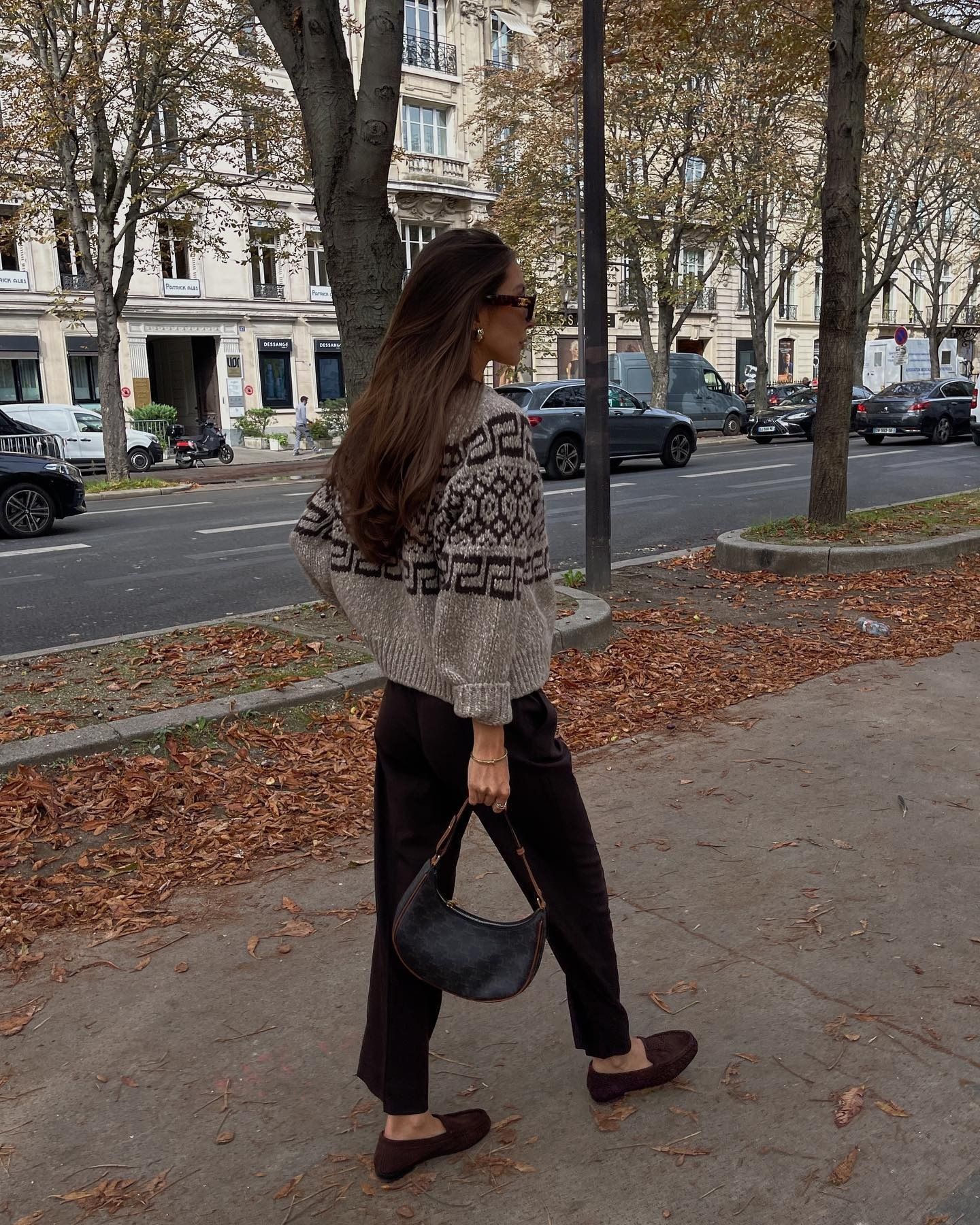 Influencer Felicia Akerstrom wears suede brown loafers, black trousers, and a patterned sweater.