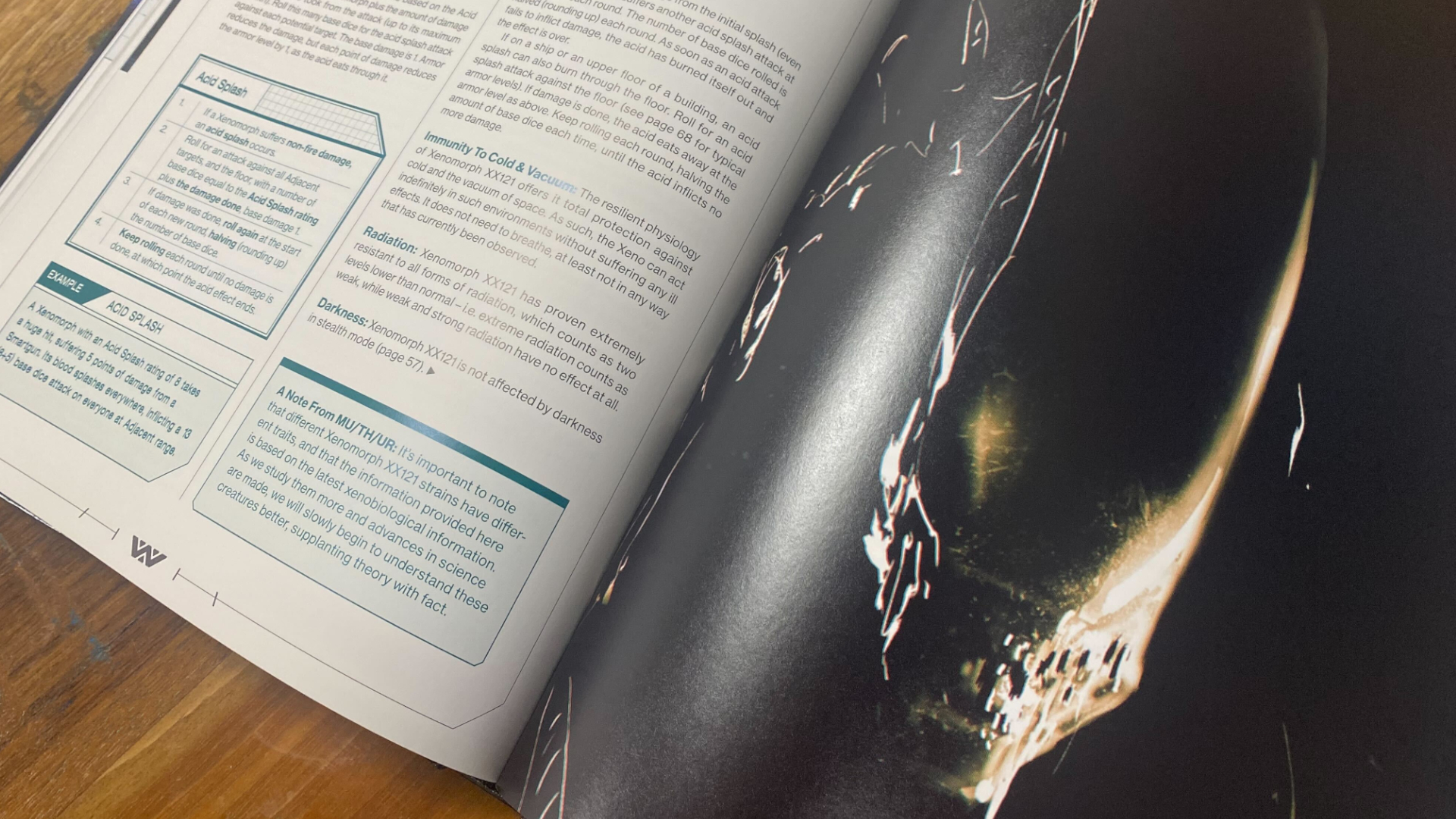 A xenomorph stares into the foreground on a page of art in the Alien RPG book, which is sitting open on a wooden surface