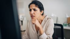 A confused woman looks at a computer screen.