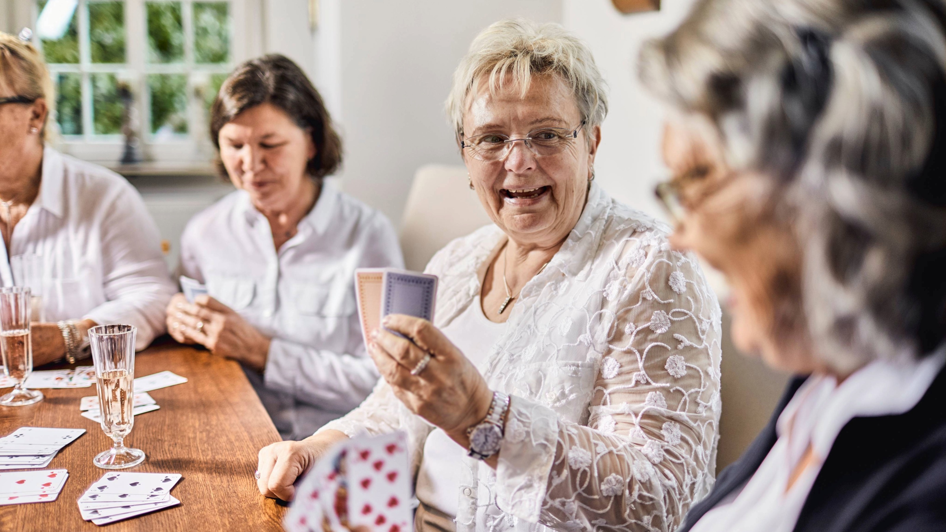 Senior female friends sitting around table playing cards
