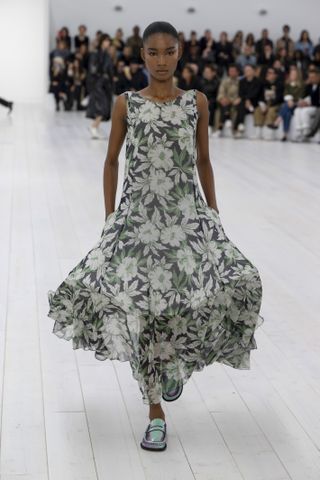 A photo of a model wearing a sheer floral Loewe dress on the runway