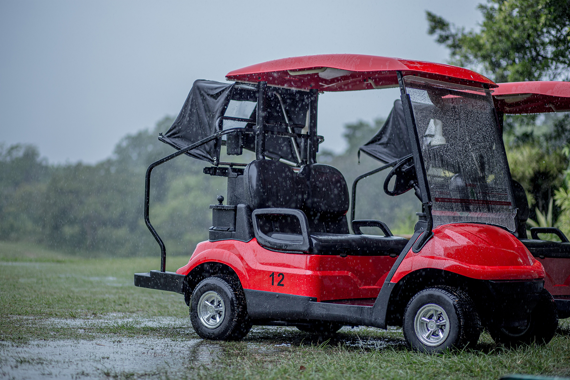 Golf buggy in heavy rain on a saturated golf course that is flooding with water