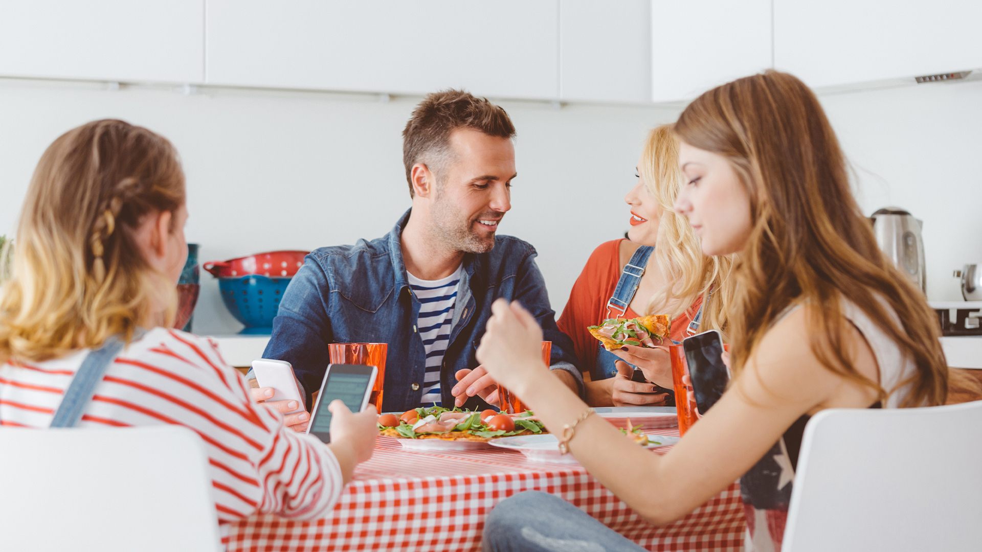 People sit at the table, eating and looking at their phones